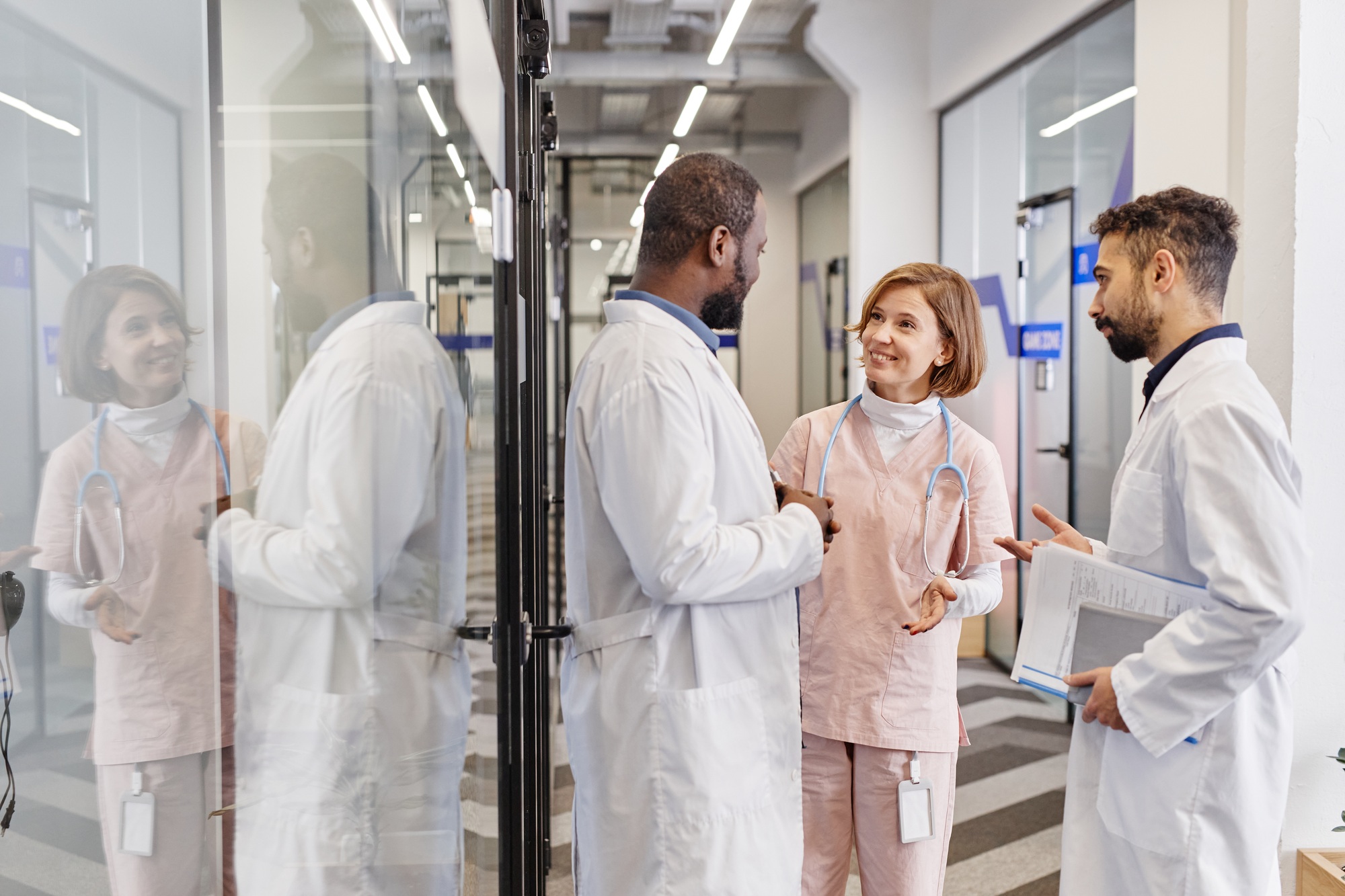 Three contemporary professional medical workers in lab coats having discussion